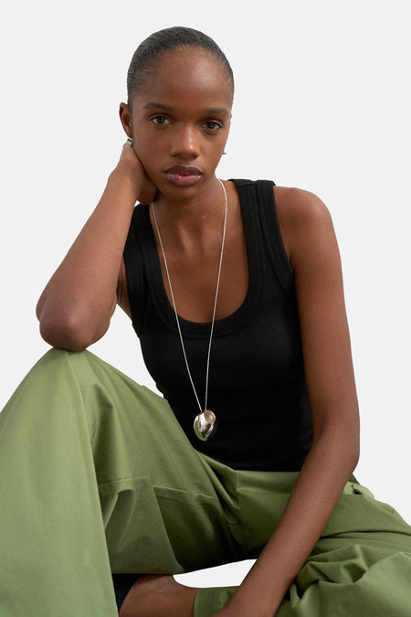 Débardeur noir de TOPSHOP, porté avec une chaîne argentée et un pantalon vert.