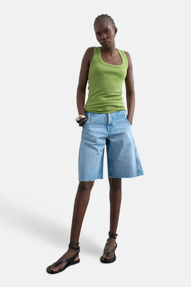 Groene tanktop van TOPSHOP, met een ribgebreide textuur, gecombineerd met losse denim shorts en zwarte sandalen met bandjes.
