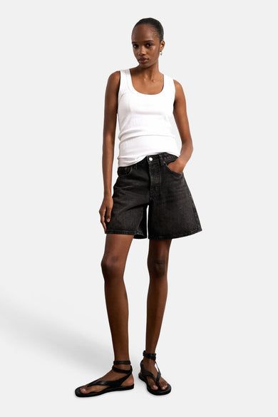 Débardeur blanc de TOPSHOP, porté avec un short en jean noir et des sandales.
