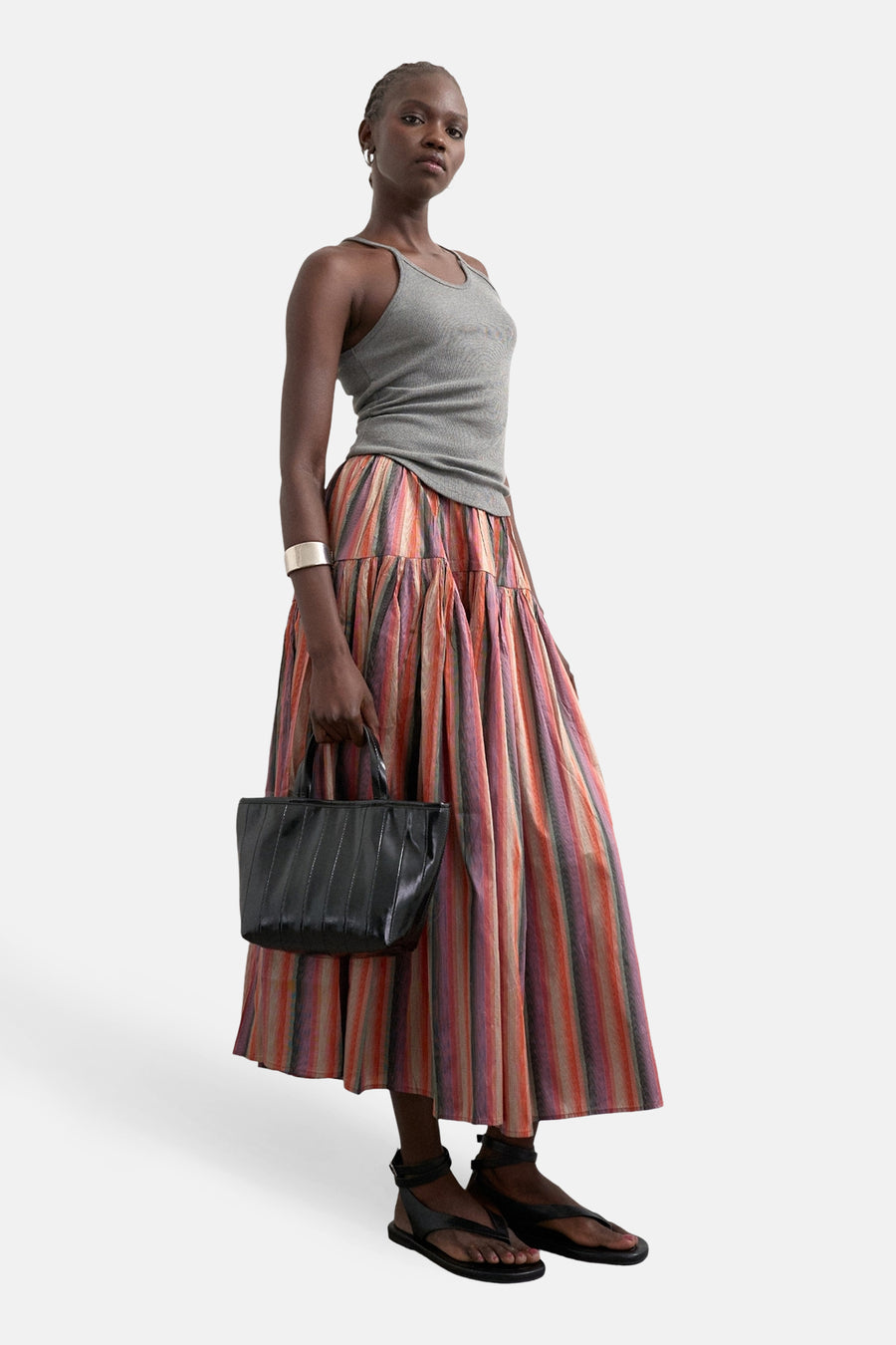 Multicolor rok van TOPSHOP, met verticale strepen en gecombineerd met een grijze top, zwarte sandalen en zwarte handtas.
