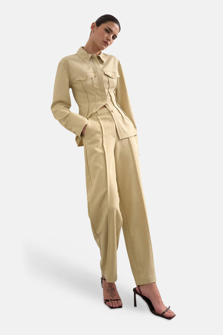 Pantalon beige de TOPSHOP, avec des plis et une jambe droite, combiné avec des talons noirs et un chemisier beige.