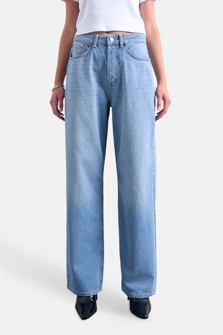 Jean droite bleu moyen de TOPSHOP, à jambes larges, porté par un mannequin avec un t-shirt blanc et des bottes noires.