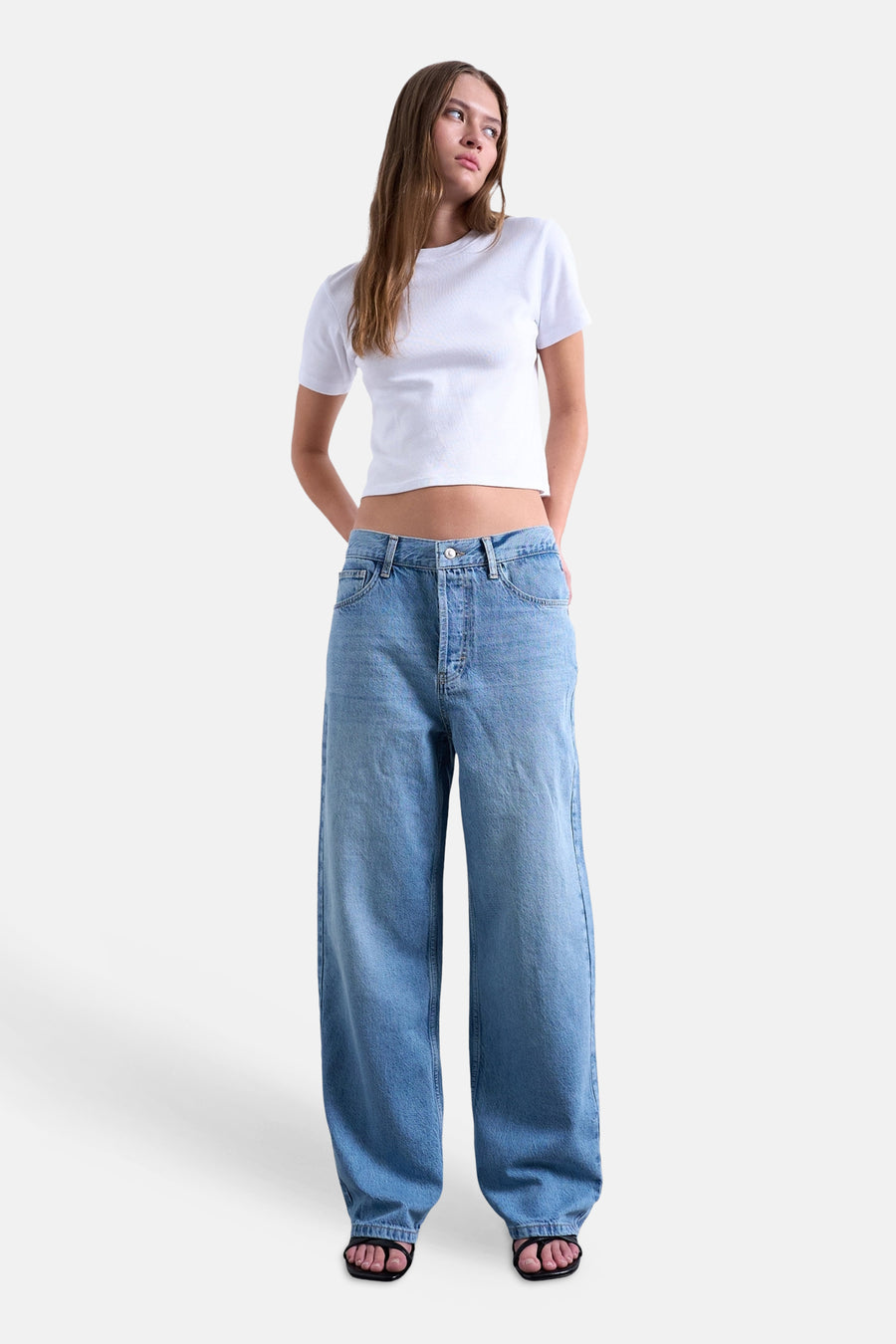 Rechte mid-blauwe spijkerbroek van TOPSHOP met wijde pijpen, gedragen door een model in een wit T-shirt en zwarte sandalen.