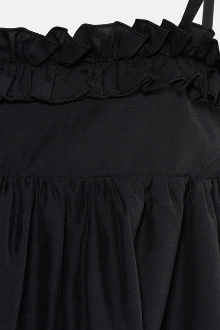 Détail d'une robe noire TOPSHOP avec volants sur le dessus et tissu plissé.