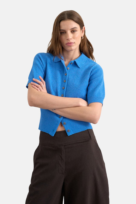 Blauwe trui van TOPSHOP, met korte mouwen en knoopsluiting, gecombineerd met een bruine broek met krijtstreep.