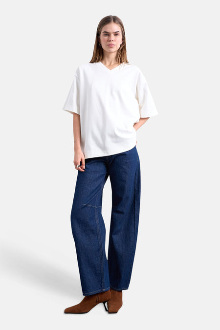 T-shirt écru de TOPSHOP à col en V, porté par un mannequin avec un jean bleu foncé et des bottines marron.