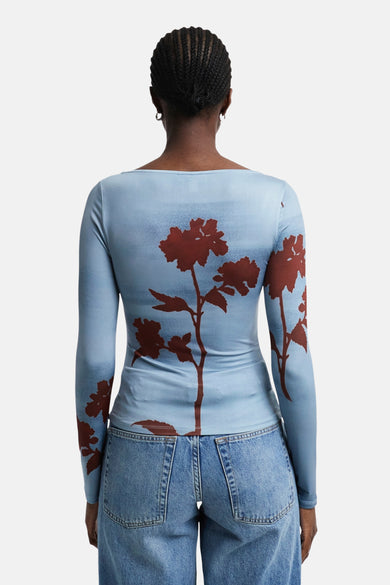 Blauw T-shirt met lange mouwen van TOPSHOP, met bruine bloemenprint op de rug, gecombineerd met een denim broek.
