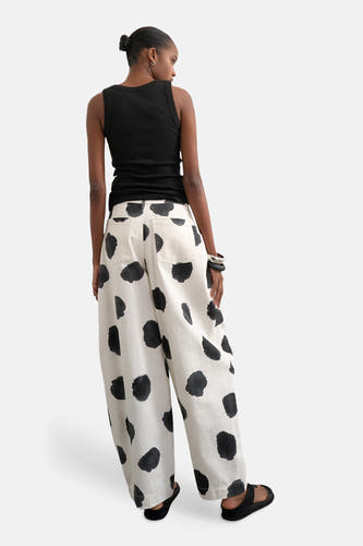 Broek ecru van TOPSHOP, met een zwart stippenpatroon, gecombineerd met een mouwloze zwarte top en sandalen.