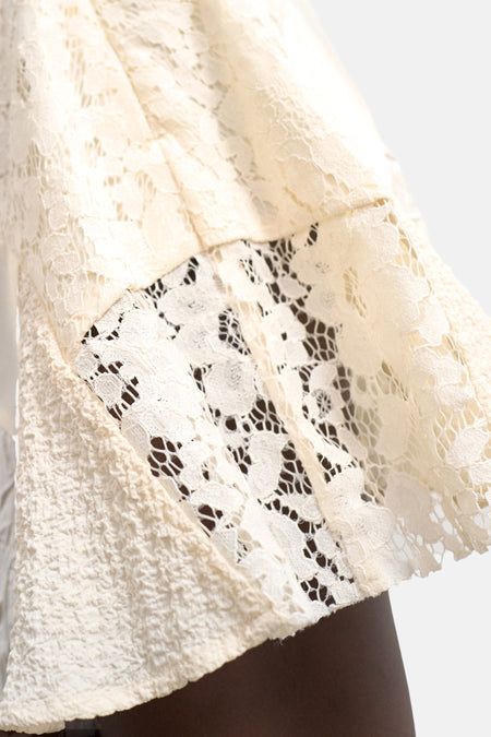 Ecru rok van TOPSHOP, close-up van delicaat kant en gekreukelde stof, met een donkere arm eronder.