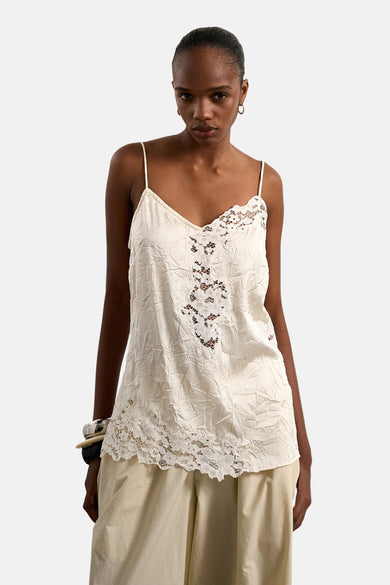 Ecru mouwloze blouse van TOPSHOP met kreukeltextuur en kanten inzetstukken, gedragen op een model met beige broek en zilveren armband.