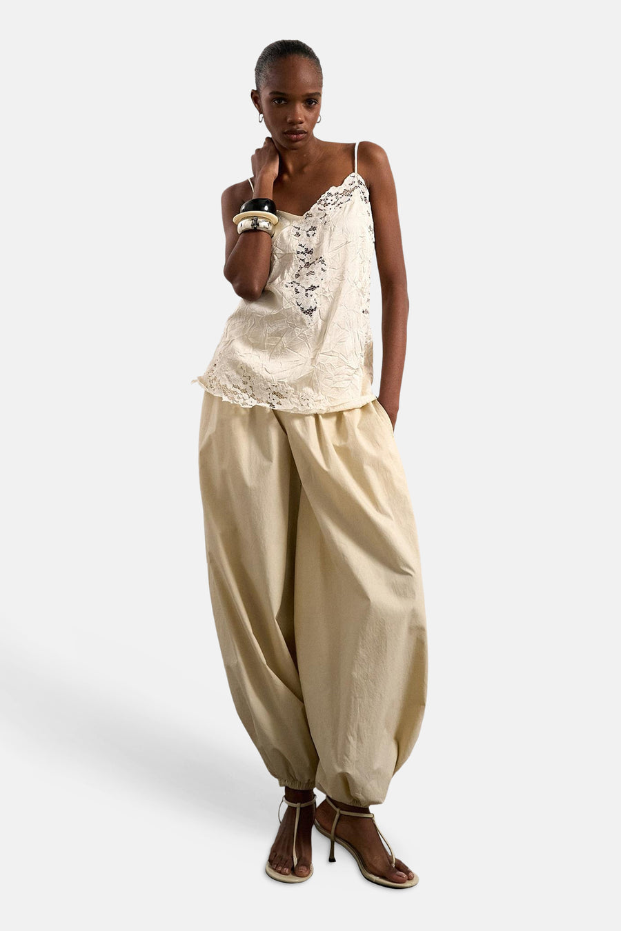 Ecru mouwloze blouse van TOPSHOP met kanten details, gedragen op een beige wijde broek en sandaaltjes met hak.