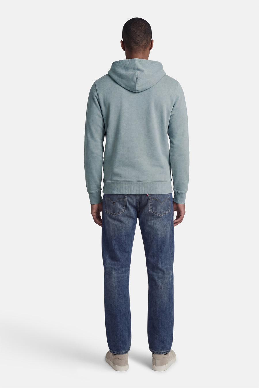 Blauwe sweater met kap van Levi's, rugzijde gezien, gecombineerd met een donkere jeans en beige sneakers.
