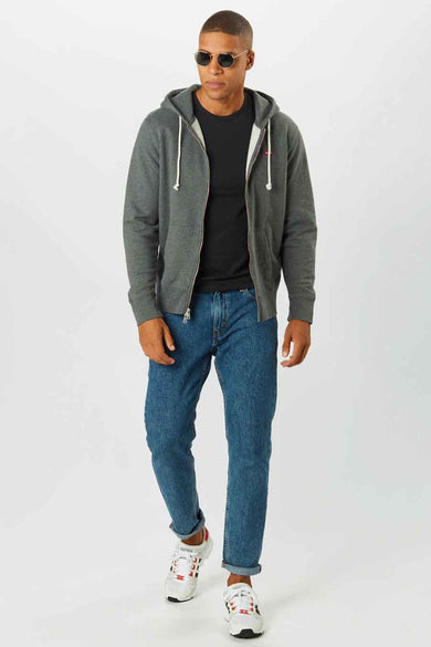 Grijze sweater met rits van Levi's, gedragen met een zwart T-shirt, blauwe jeans en witte sneakers.