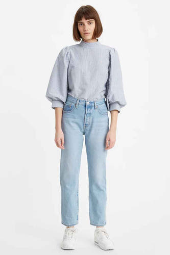 Lichtblauwe straight jeans van Levi's, gedragen met gestreepte blouse en witte sneakers.