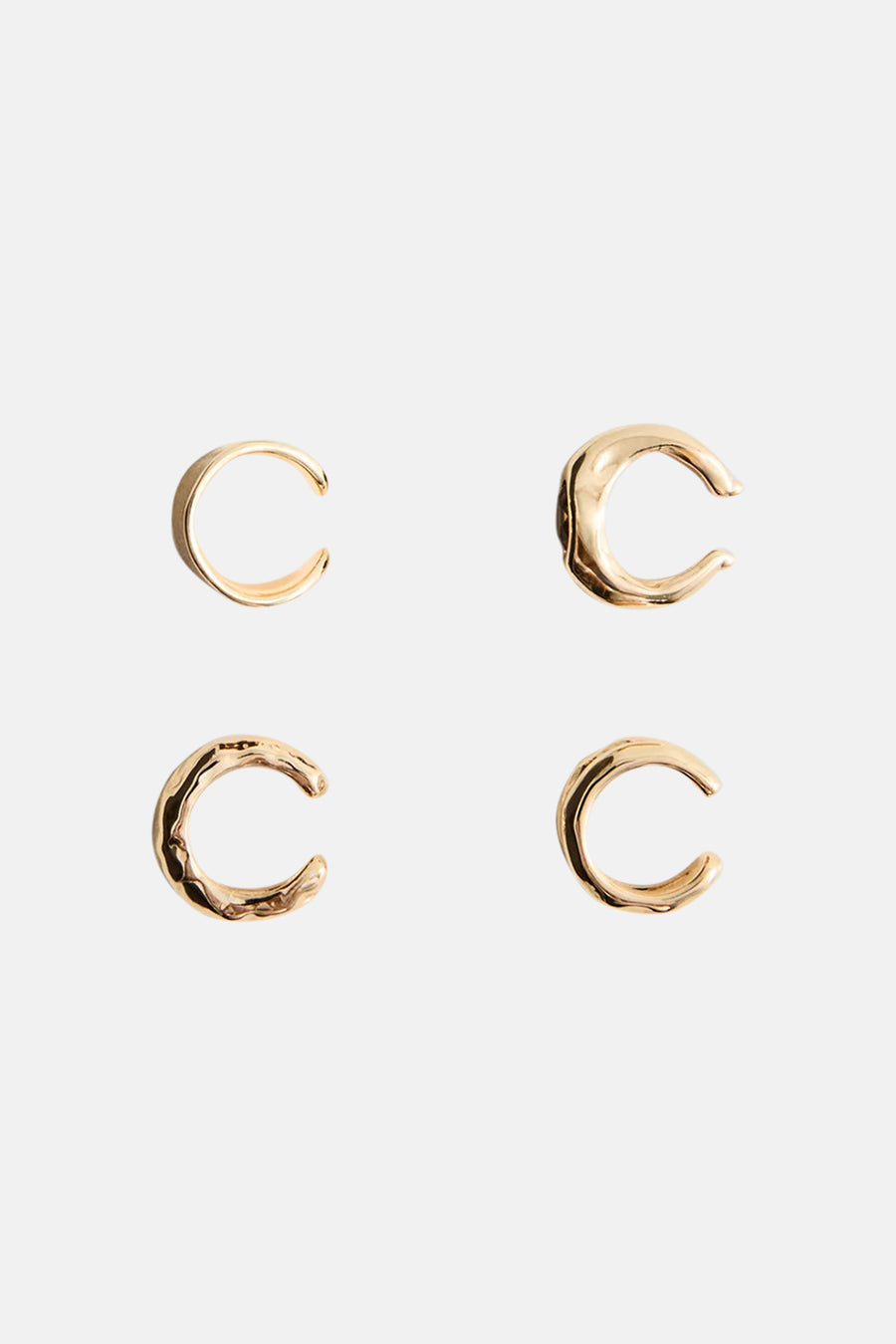 Gouden oorringen van MANGO, vier kleine C-vormige ringen met gladde en getextureerde oppervlakken, minimalistisch design, witte achtergrond