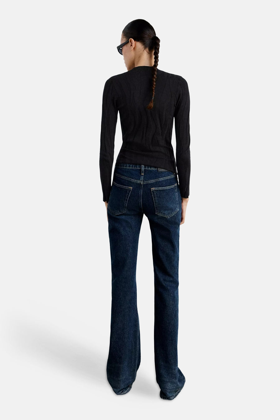 Zwart gebreid trui met ronde hals van MANGO, achterzijde weergegeven, met fijn kabelpatroon en strakke pasvorm, gedragen met donkerblauwe flared jeans.