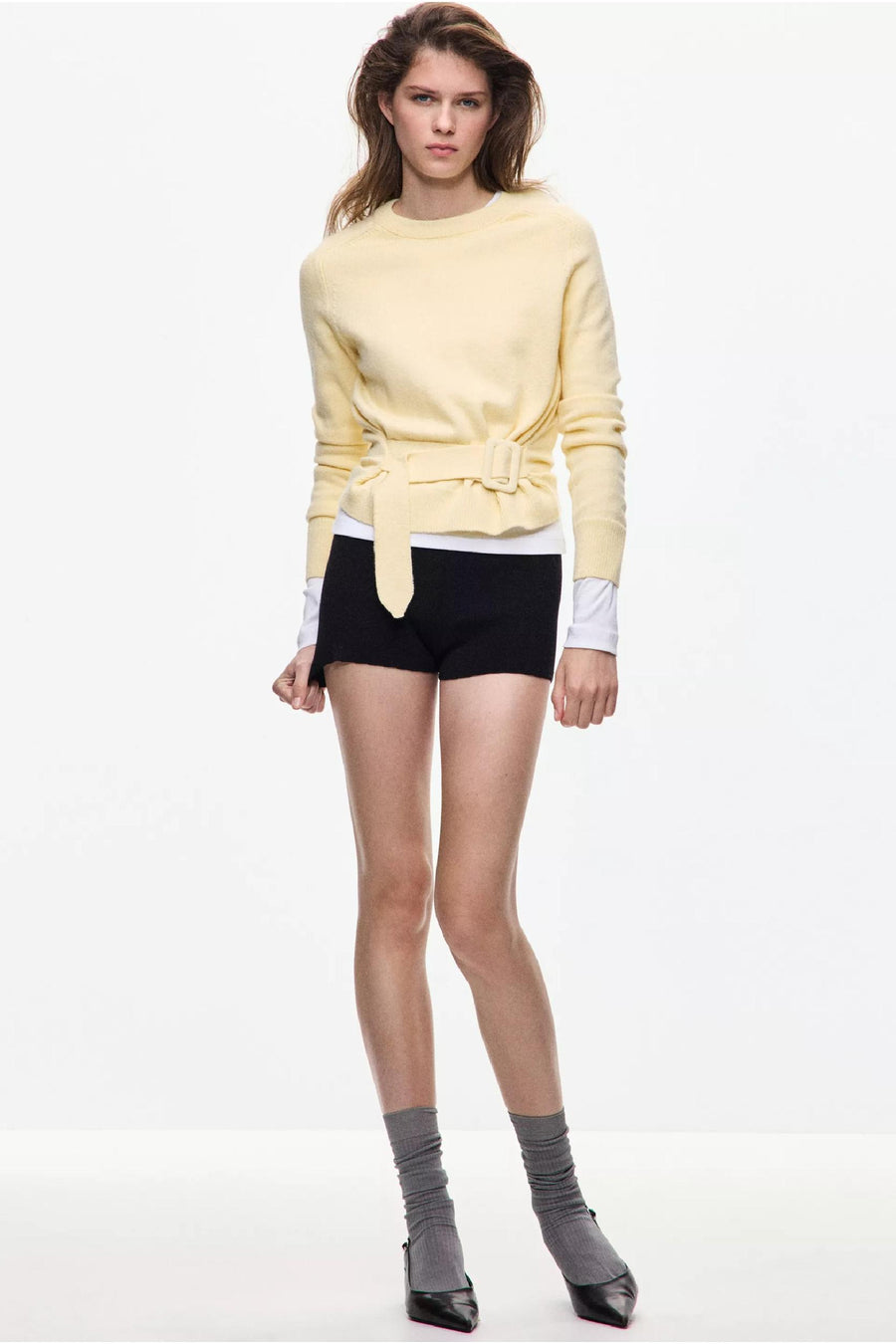 Gele ronde hals trui met riem van MANGO, gedragen met zwarte shorts en grijze sokken, front view