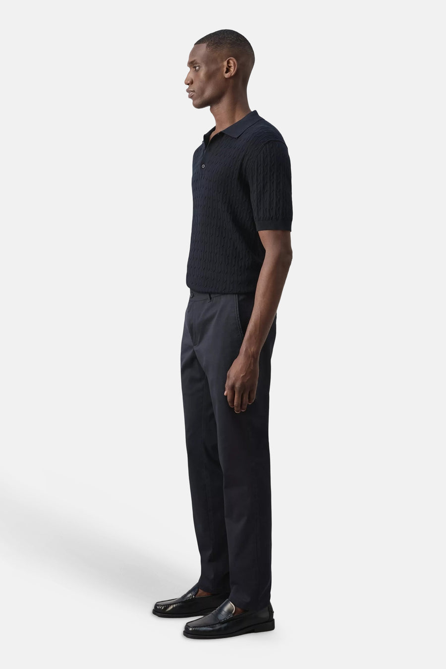 Blauwe chino's van MANGO, zijprofiel, gestreept overhemd, zwarte loafers, strakke pasvorm