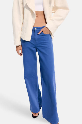 Blauwe damesbroek met wijde pijpen van MANGO, 5-pocket stijl, gedragen met crèmekleurige jas en zwarte sandalen, front view