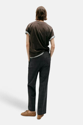 Grijze chino broek van MANGO, achterzijde, met subtiel ruitpatroon, rechte pasvorm, model draagt donkere t-shirt en bruine loafers