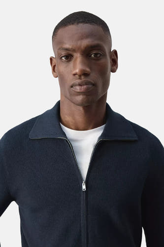 Blauwe ribbelpull met rolkraag van MANGO, voorzien van rits, gedragen over een wit T-shirt, close-up front view