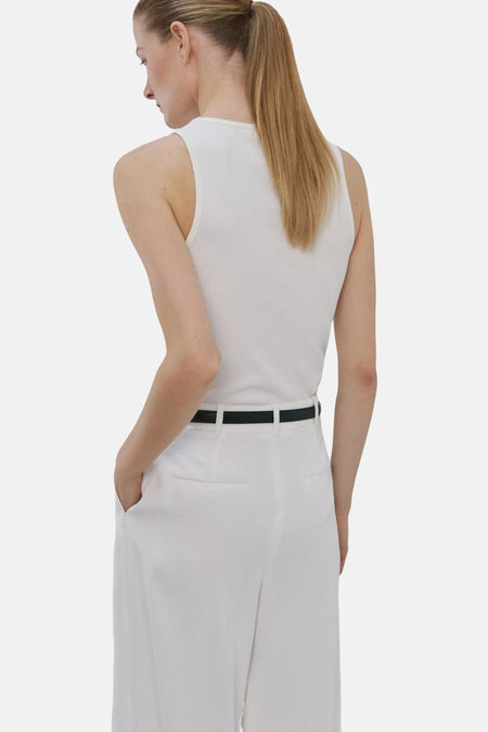 Witte ribbel tanktop van MANGO, achterkant weergegeven, met strakke pasvorm en zwarte riem, model in witte broek