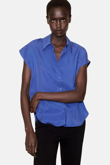 Blauw mouwloos overhemd van MANGO, gestikt met knopen, zacht glanzend materiaal, model in front view met zwarte broek