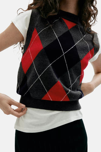 Multicolor geruit gilet van MANGO, met rode, zwarte en grijze ruitjes, gedragen over een witte t-shirt, close-up voorzijde.