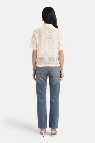 Beige blouse met korte mouwen van Terra di Siena, openwerk met bloemmotief, rugaanzicht, gedragen op jeans en hakken.