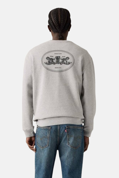 Pull-over gris de Levi's avec col rond et logo sur le dos, porté avec des jeans bleus.