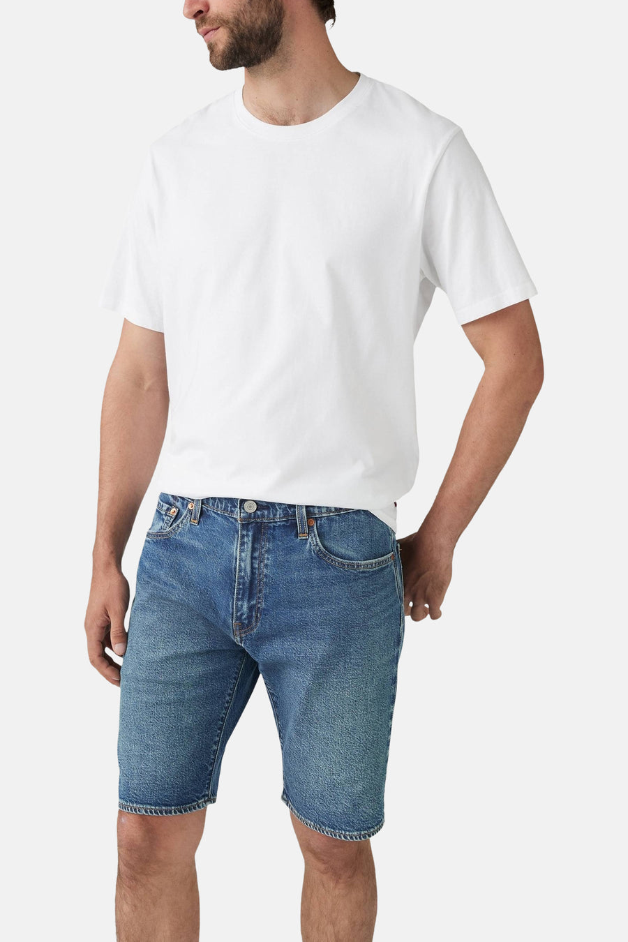 Man met wit T-shirt en blauwe denim shorts.
