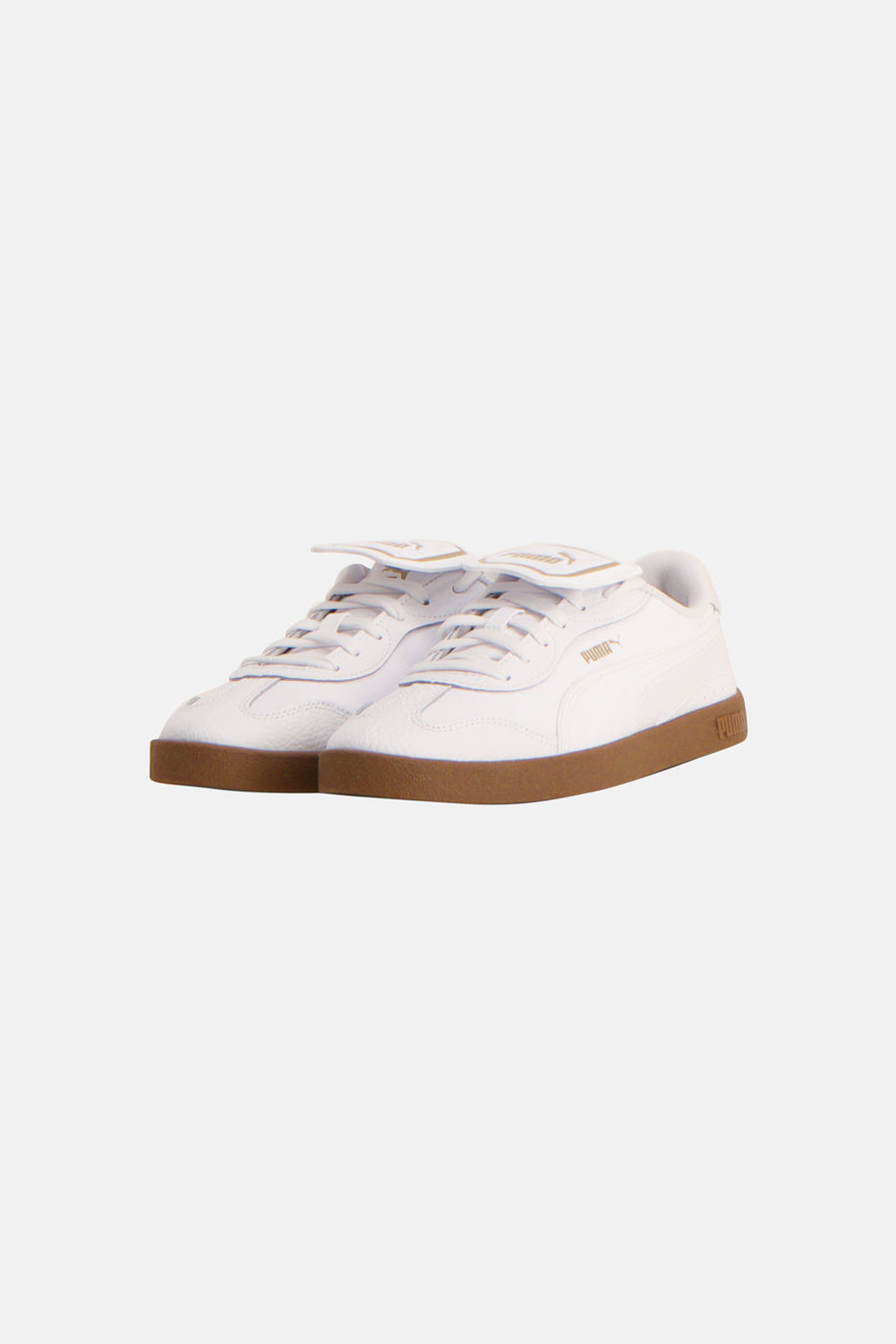 Sneakers blanches de PUMA avec un logo doré sur la langue et une semelle brune.