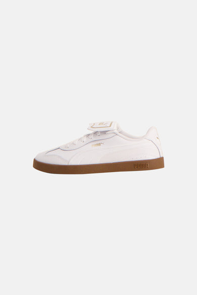 Witte sneakers van PUMA met bruine zool en het PUMA-logo in het goud.
