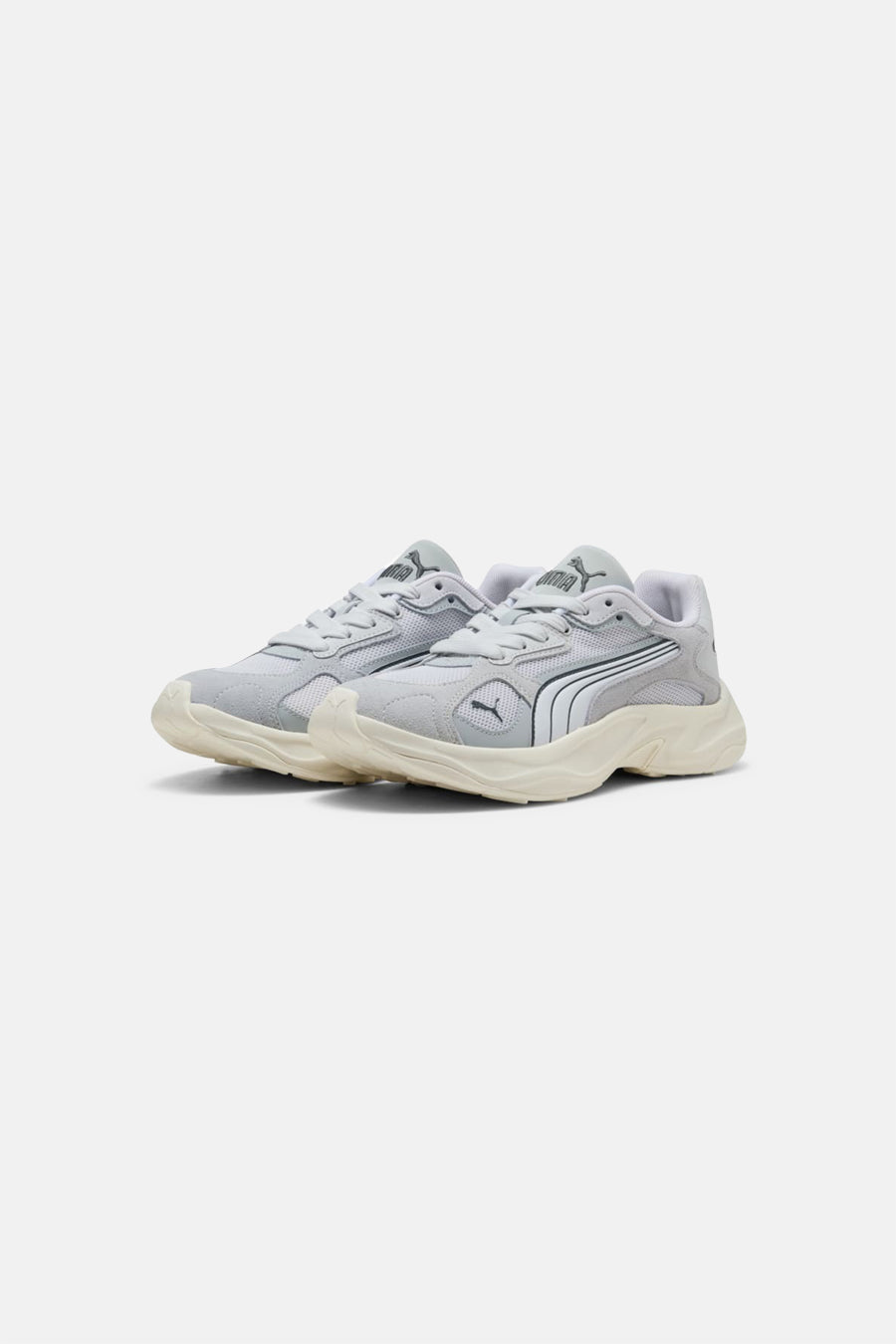 Twee grijze sneakers van PUMA met een dikke, crèmekleurige zool en witte strepen aan de zijkant.