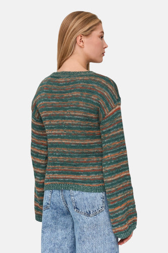 Achterkant van een vrouw die een groen gestreepte trui en blauwe jeans draagt.