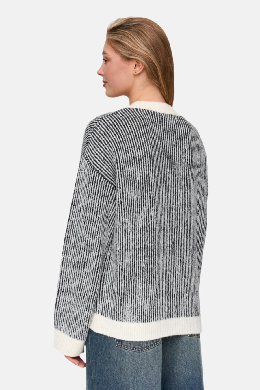 Staande vrouw, gestreepte trui met lange mouwen, denim broek.