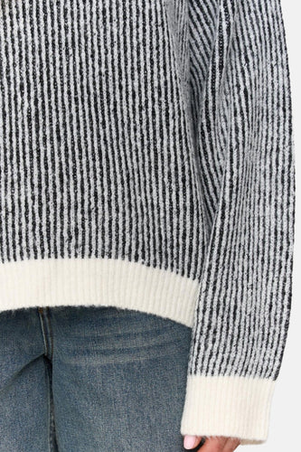 Trui met zwarte strepen en jeans.