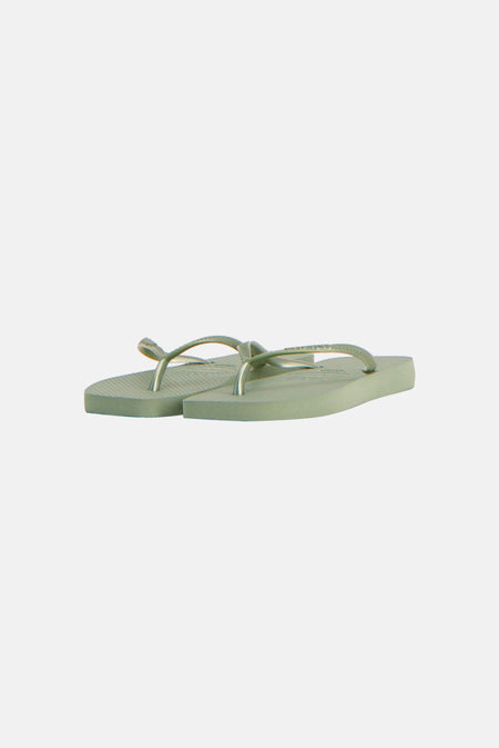 Groene slippers van Havaianas met dunne bandjes en een gestreepte zool, schuin geplaatst.