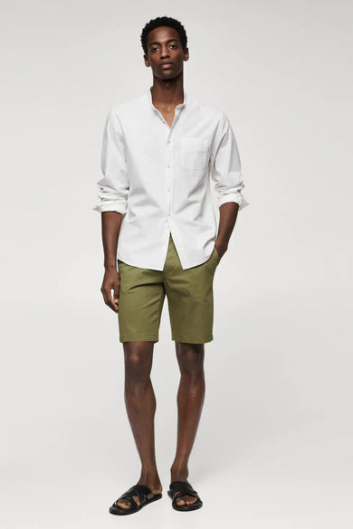 Beige short van MANGO, gedragen met een wit overhemd en zwarte sandalen.