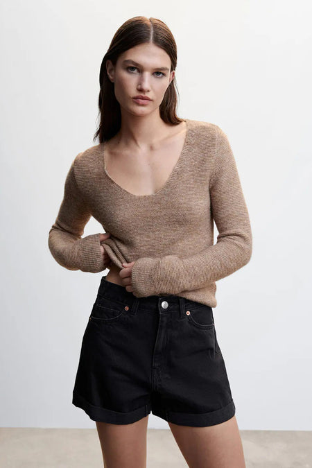 Zwarte 5-pocket shorts van MANGO, met opgerolde pijpen en klassieke zakken, gedragen met een beige trui in lifestyle-opname.