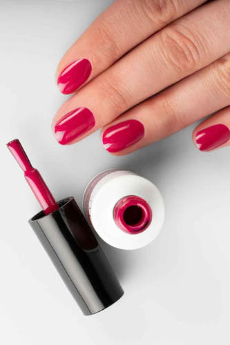 Fuchsia gel nagellak van Pn Selfcare, met een open flesje en een hand met gelakte nagels.
