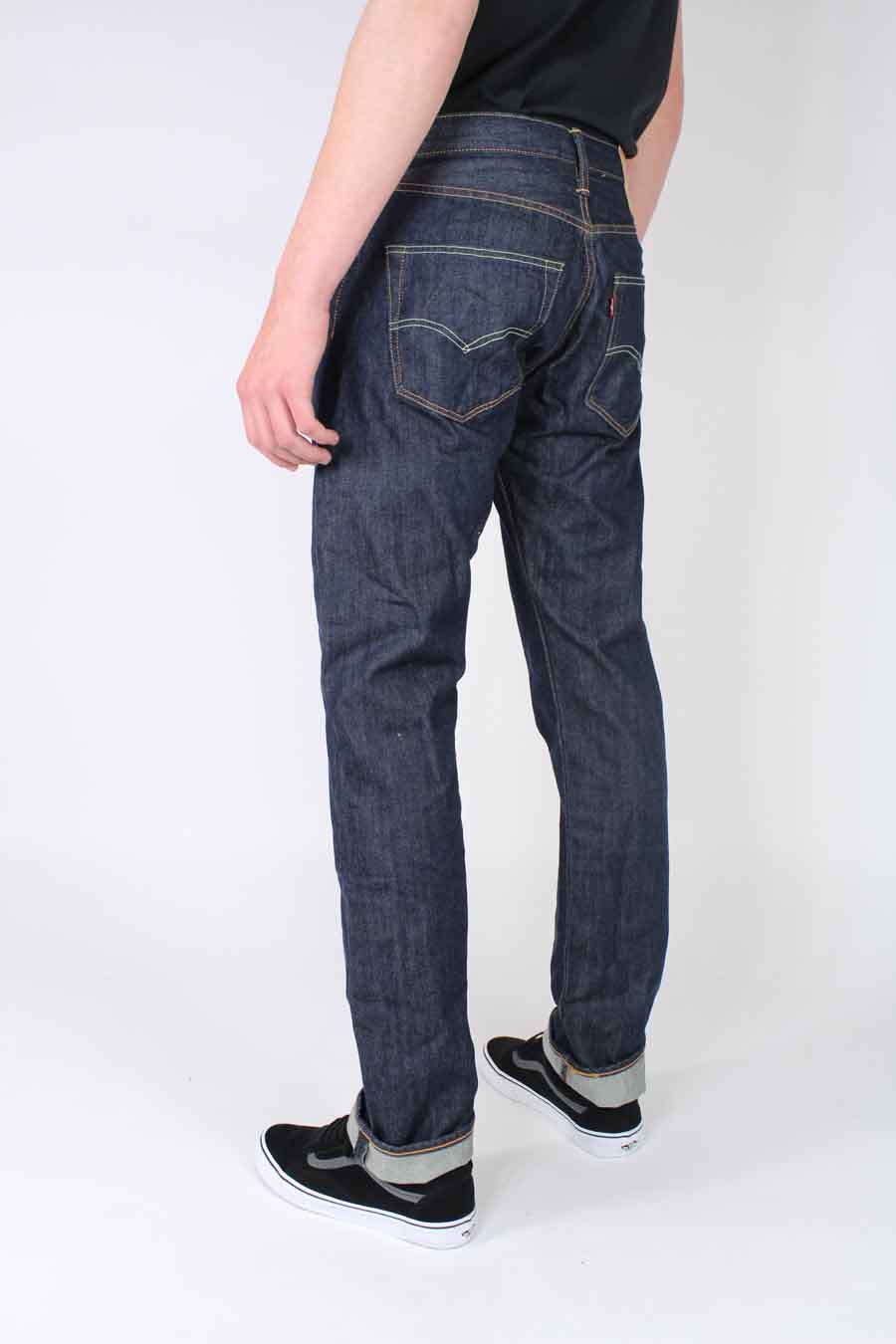Donkerblauwe straight jeans van Levi's, met zichtbare stiksels en opgerolde pijpen, gezien van achteren.