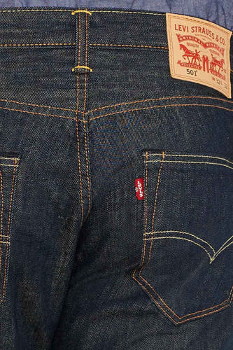 Donkerblauwe rechte jeans van Levi's, met een rode merklabel op de achterzak en een bruin leren label op de tailleband.