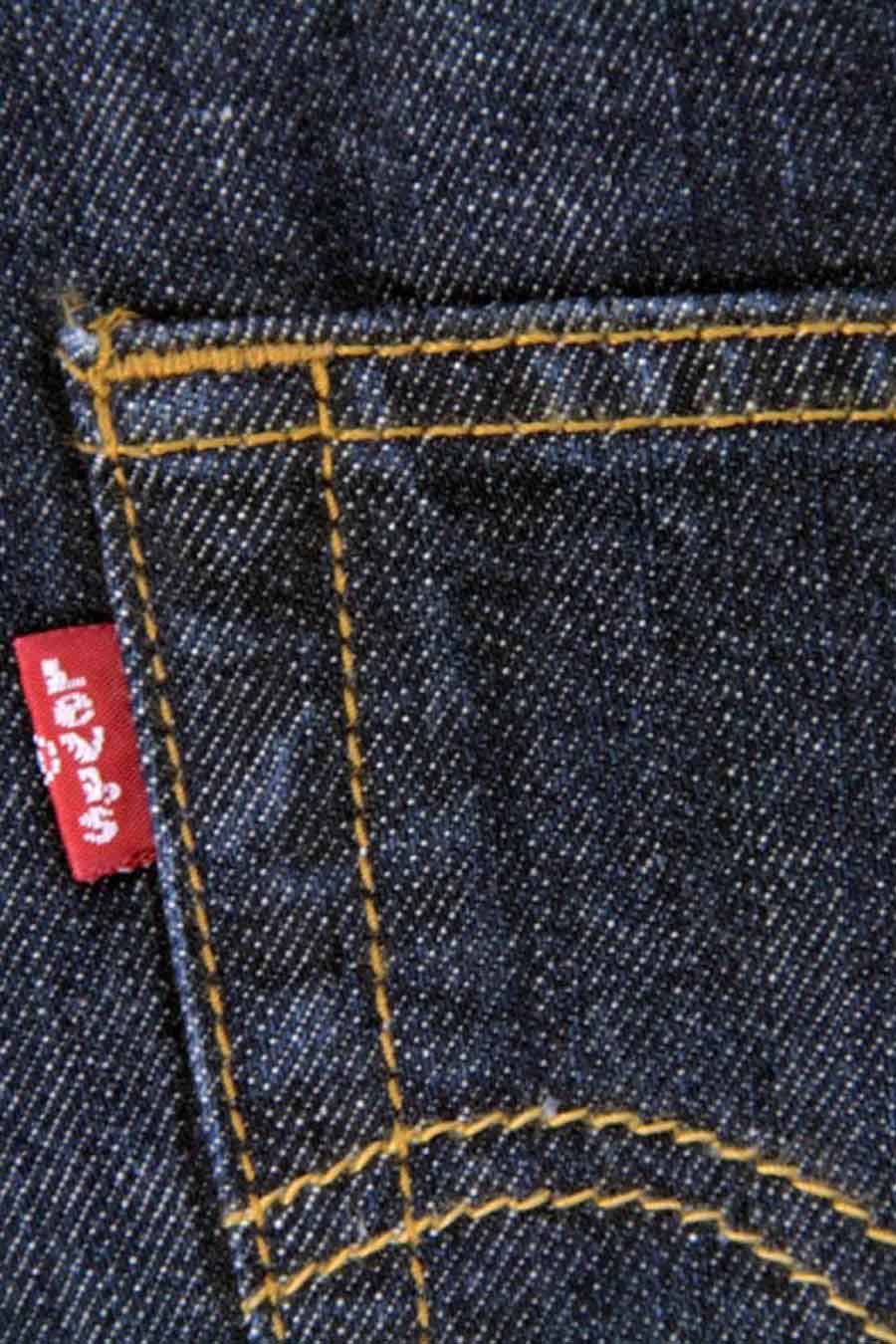 Donkerblauwe straight jeans van Levi's, met geel stiksel en een rode merklabel op de achterzak.
