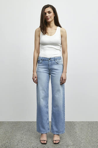Lichtblauwe wijde jeans van PULZ, gecombineerd met een wit tanktop en zwarte sandalen.