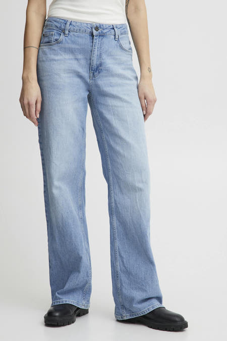 Lichtblauwe wide jeans van Pulz, gecombineerd met zwarte schoenen, en met een tattoo op de arm.
