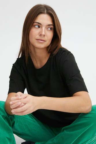 Zwart T-shirt met korte mouwen van PULZ, gedragen met een groene broek.