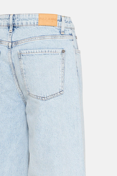 Lichtblauwe wijde jeans van PULZ JEANS, met een achterzak en een lederen label op de tailleband.
