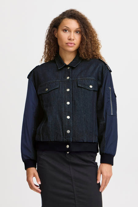 Donkerblauwe denim jeansjas van PULZ, met lange contrasterende mouwen en zilverkleurige knoopsluiting.
