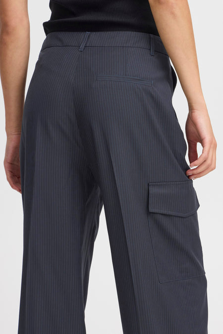Pantalon bleu de PULZ, avec une ligne de craie et un sac cargo sur la jambe droite.